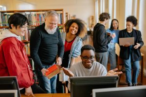A diverse group of students collaborating in a library setting, sharing ideas and technology.