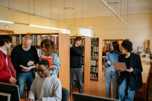 A diverse group of students engage in study activities in a bright library setting.